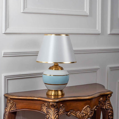 Blue and white ceramic table lamp with golden details and a white shade exuding sophistication even when unlit perfect for interior styling.