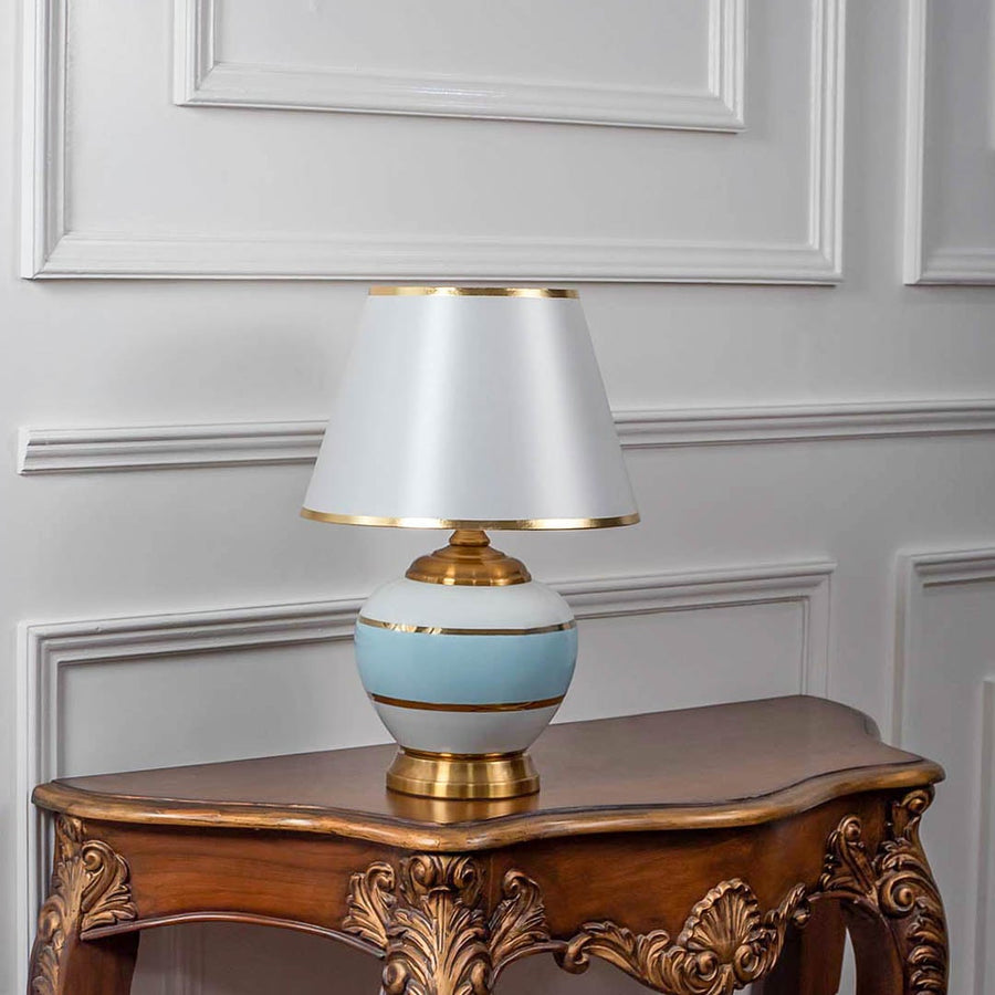 Blue and white ceramic table lamp with golden details and a white shade exuding sophistication even when unlit perfect for interior styling.