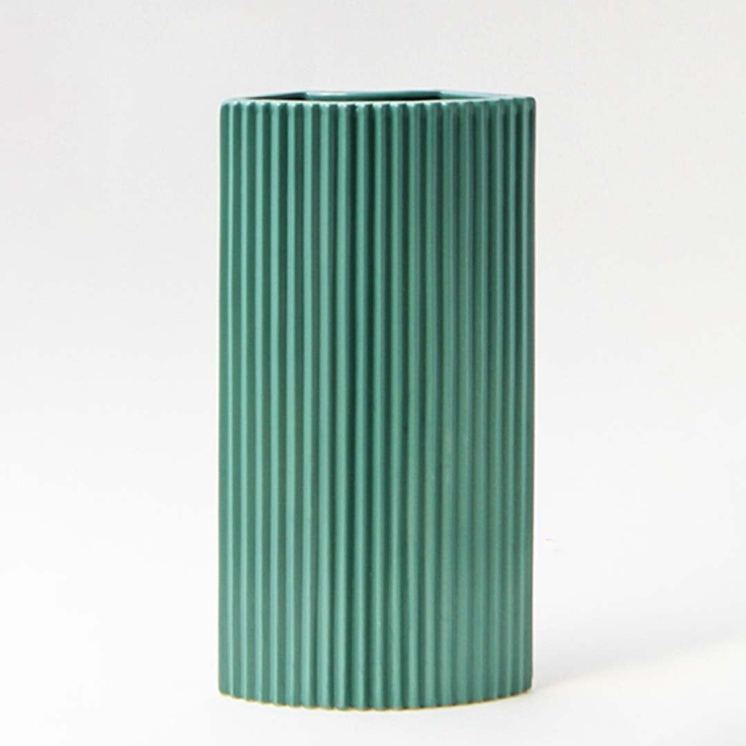 Contemporary teal ceramic vase with ribbed detailing against a dark background creating a refined contrast.