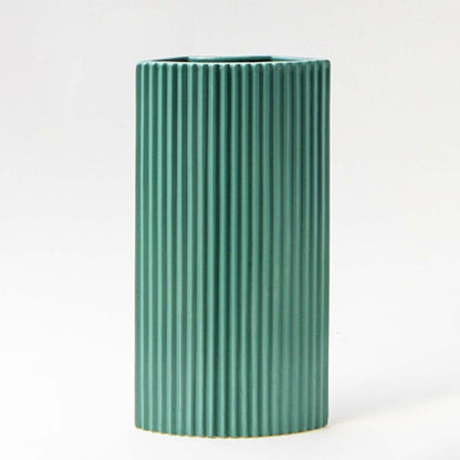 Contemporary teal ceramic vase with ribbed detailing against a dark background creating a refined contrast.