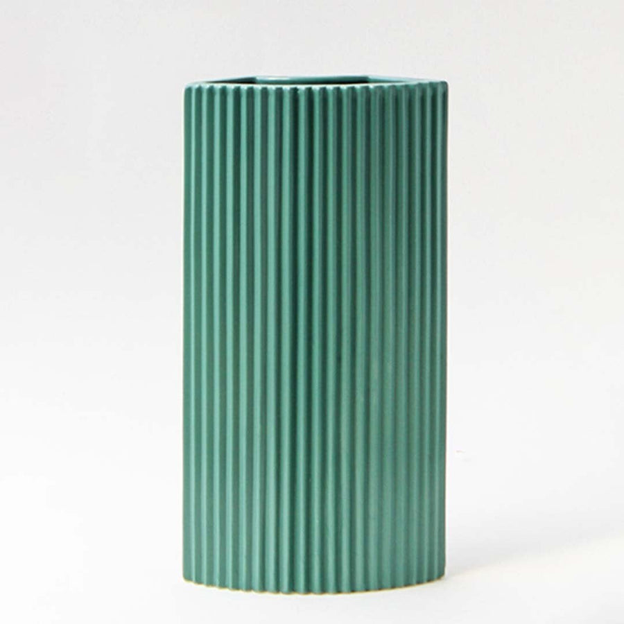 Contemporary teal ceramic vase with ribbed detailing against a dark background creating a refined contrast.
