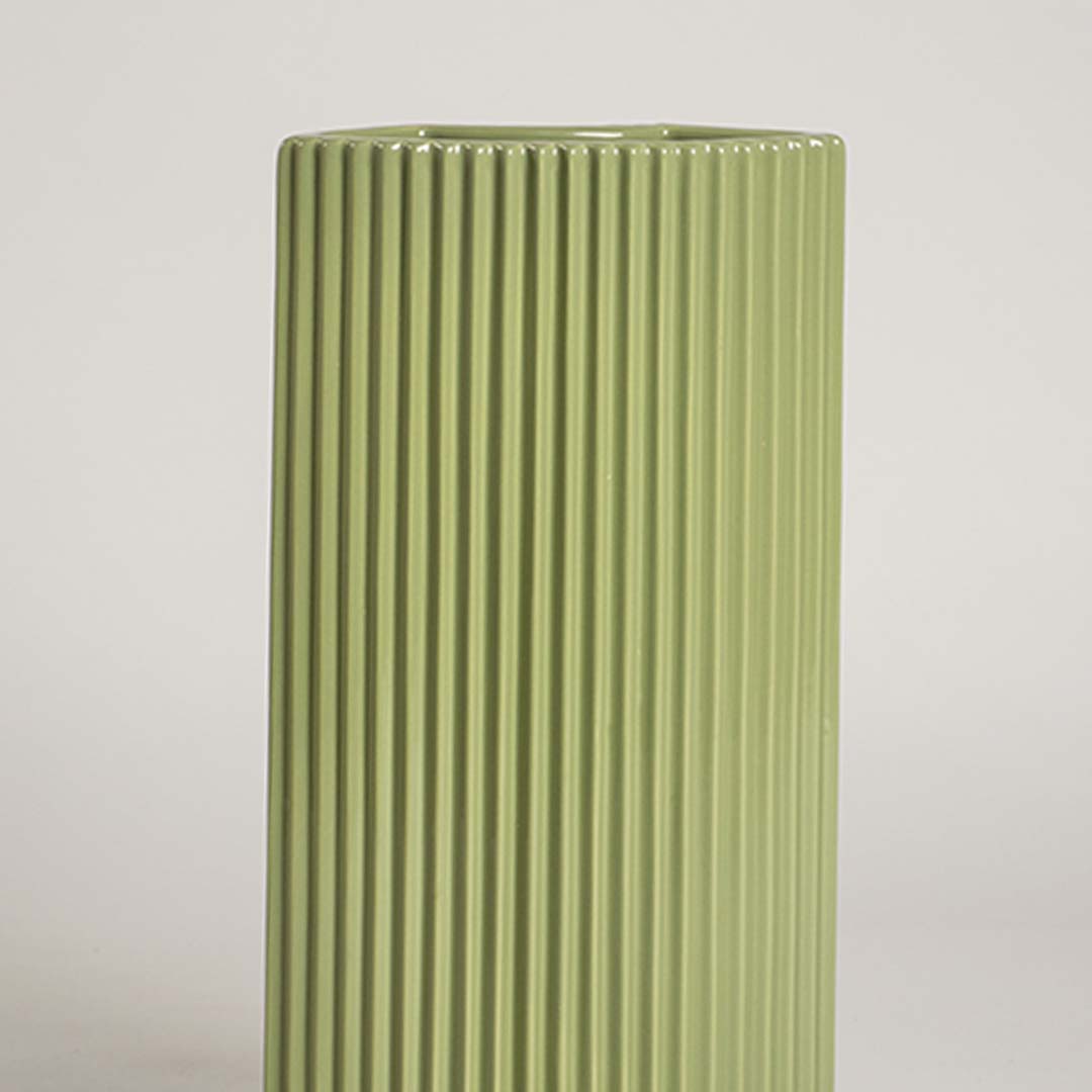 Closeup view of the green decorative vase highlighting its smooth glossy finish and crisp vertical ribbed lines that enhance its modern sculptural look in detail.