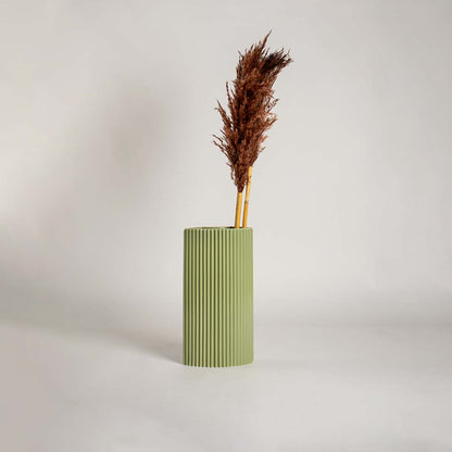 Soft green modern vase displayed in a clean minimal setting showing its tall structured form and vertical ribbed detailing that adds a refined decorative touch to any space.