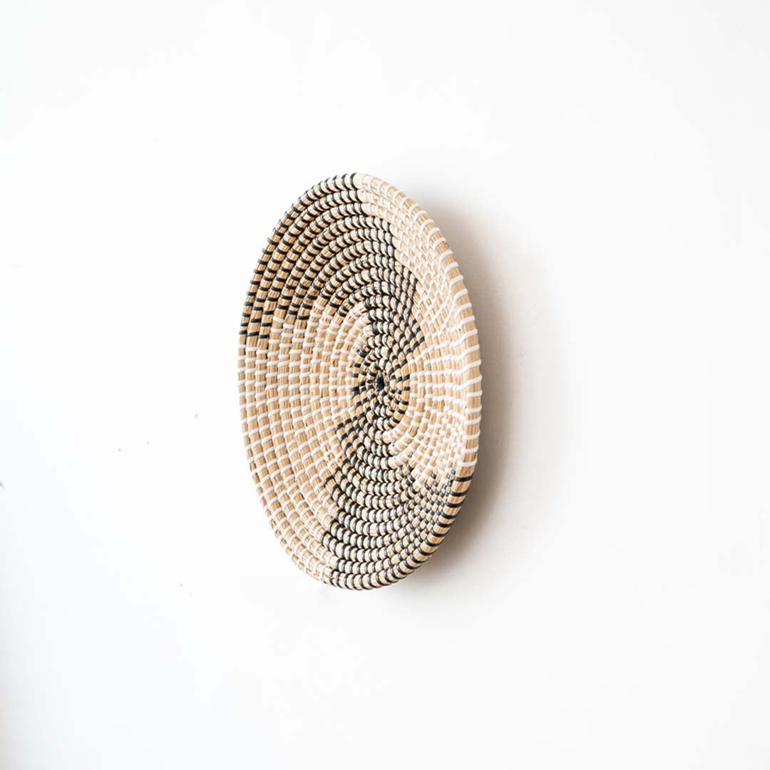 Side view of handwoven wall basket decor made of rustic natural fiber with boho abstract design for wall styling.