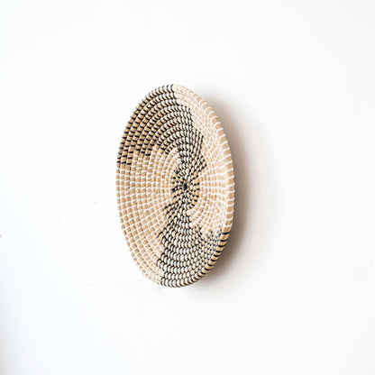 Side view of handwoven wall basket decor made of rustic natural fiber with boho abstract design for wall styling.