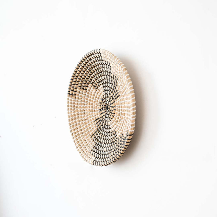 Side view of handwoven wall basket decor made of rustic natural fiber with boho abstract design for wall styling.