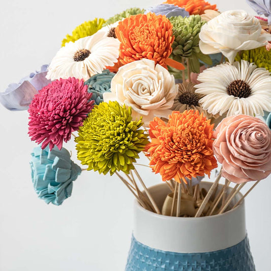 Closeup of blue ceramic vase showing intricate cross pattern and vibrant artificial flower details for modern decor.