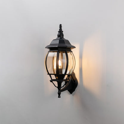 Black metal outdoor lantern wall light on white background with clear ribbed glass for patio decor.