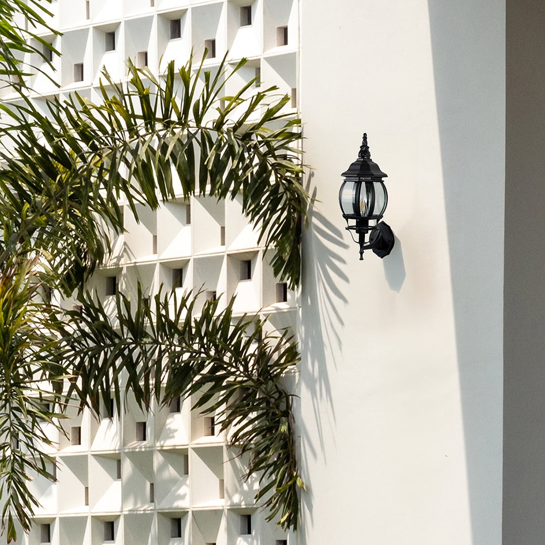 Black upward wall sconce with cage glass globe illuminating entrance creating elegant vintage outdoor porch lighting style.