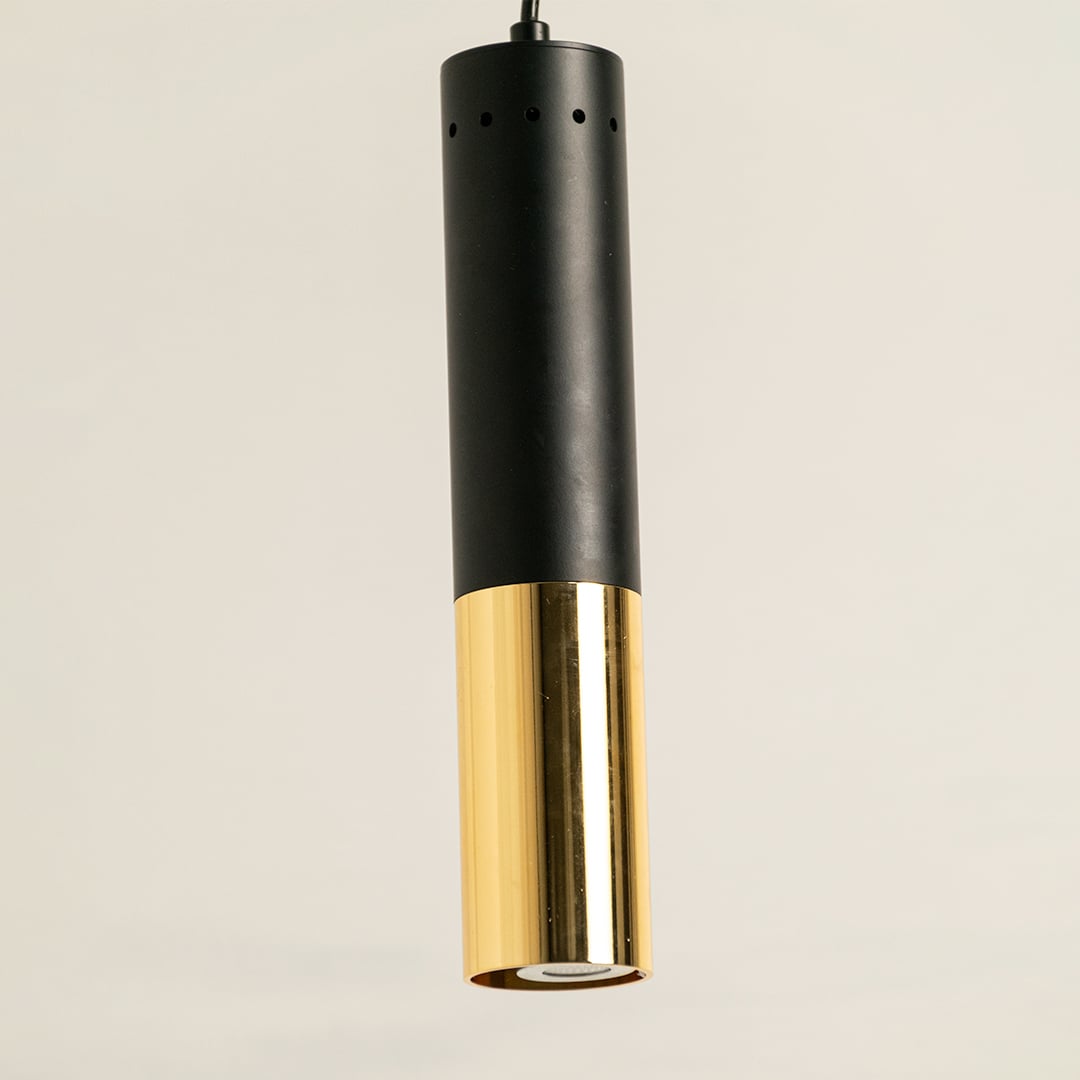 Black and gold cylinder pendant light shown in close up view against plain background for modern minimalist décor.