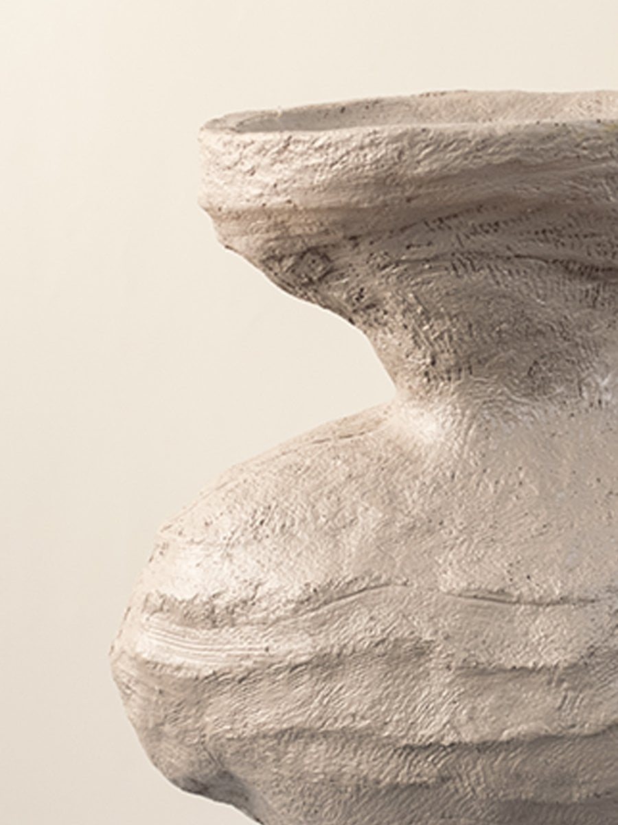 Closeup of beige ceramic vase showing textured sculptural details and artistic organic shape for home styling.