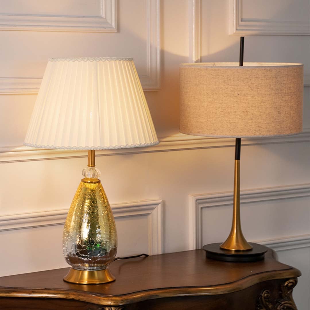 Aurora glass lamps grouped with pleated white shades turned on and golden crackle bases perfect for luxury modern home decoration.