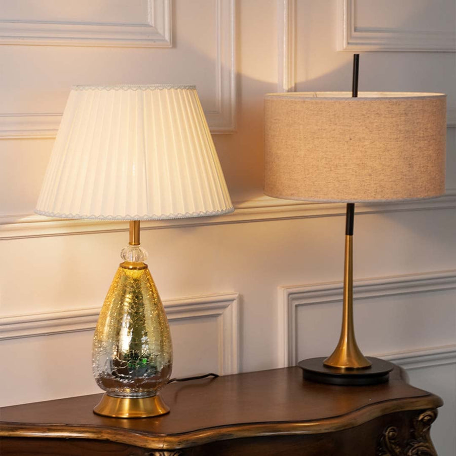 Aurora glass lamps grouped with pleated white shades turned on and golden crackle bases perfect for luxury modern home decoration.