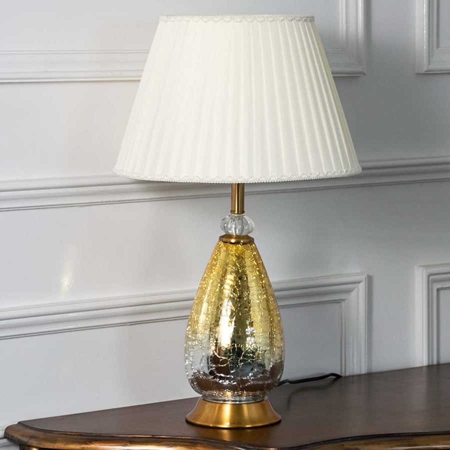 Aurora glass lamp with golden base and white pleated shade displayed on plain background with light turned off for styling.