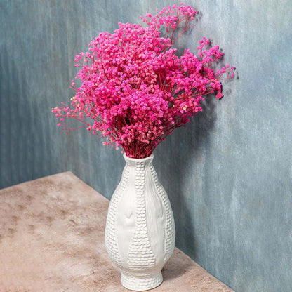 White textured ceramic vase styled with soft pink flowers placed for modern home decor.