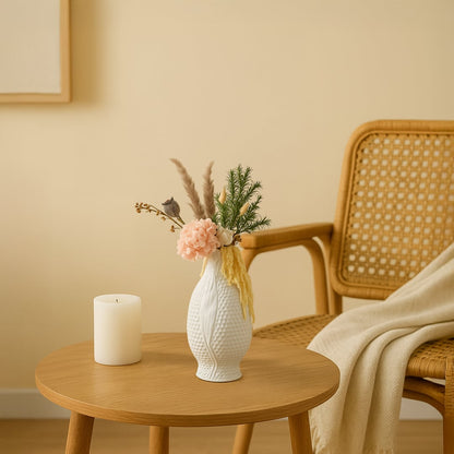 Handcrafted white ceramic vase with floral arrangement placed near a wooden chair and beige background adding elegance to modern living space.