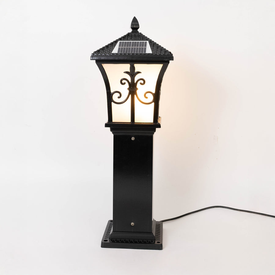 Vintage black outdoor gate light with warm glowing glass panels for elegant exterior decor use.
