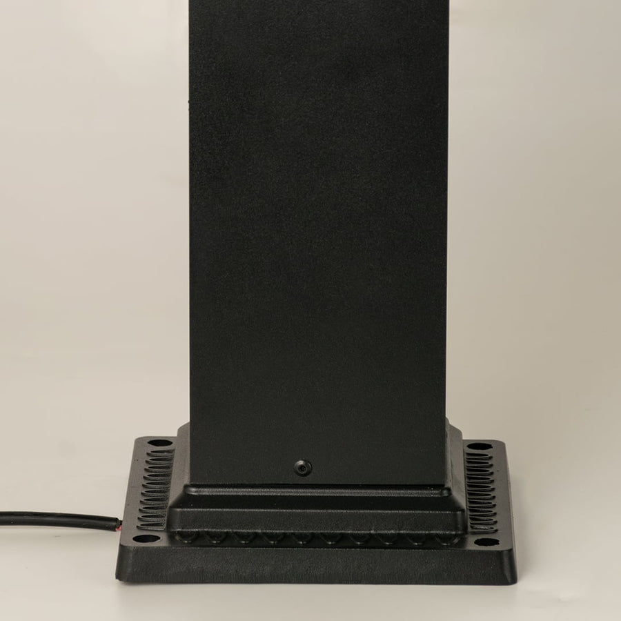 Closeup of black outdoor pillar lamp showing clear framed glass and warm filament bulb detail suitable for elegant garden and pathway lighting.