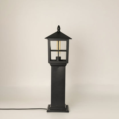 Black outdoor pillar lamp with clear glass shown with light off on a white background displaying its structured frame and elegant outdoor form.