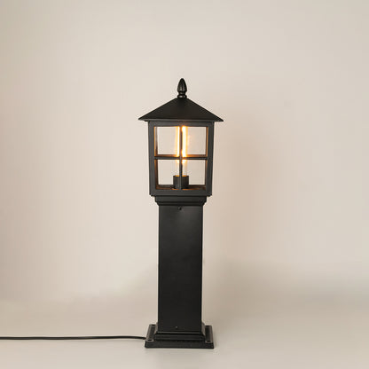 Modern black outdoor bollard light with warm glowing bulb for elegant exterior decor styling use.