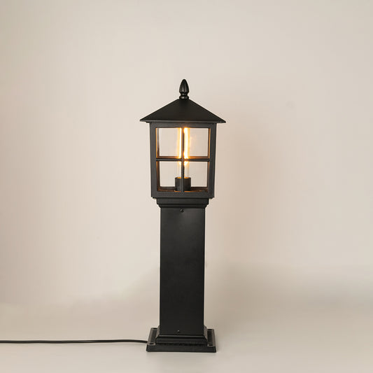 Modern black outdoor bollard light with warm glowing bulb for elegant exterior decor styling use.