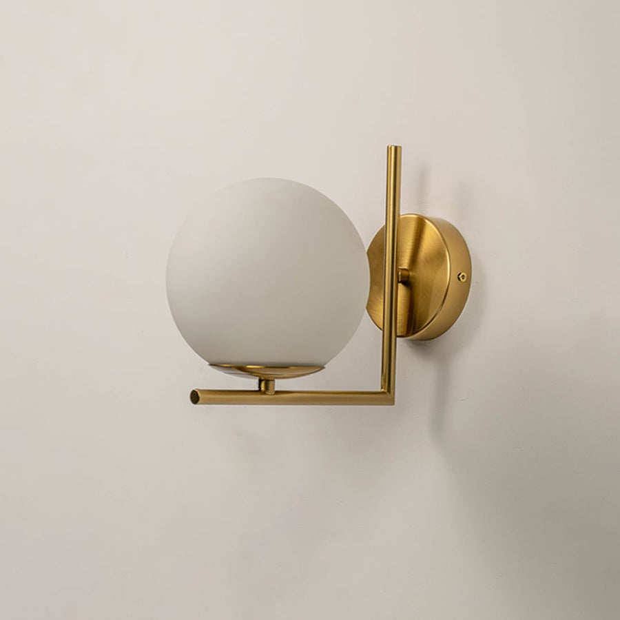 Wall light with gold metal body and frosted glass globe shade turned off suitable for modern bedroom and hallway decor.
