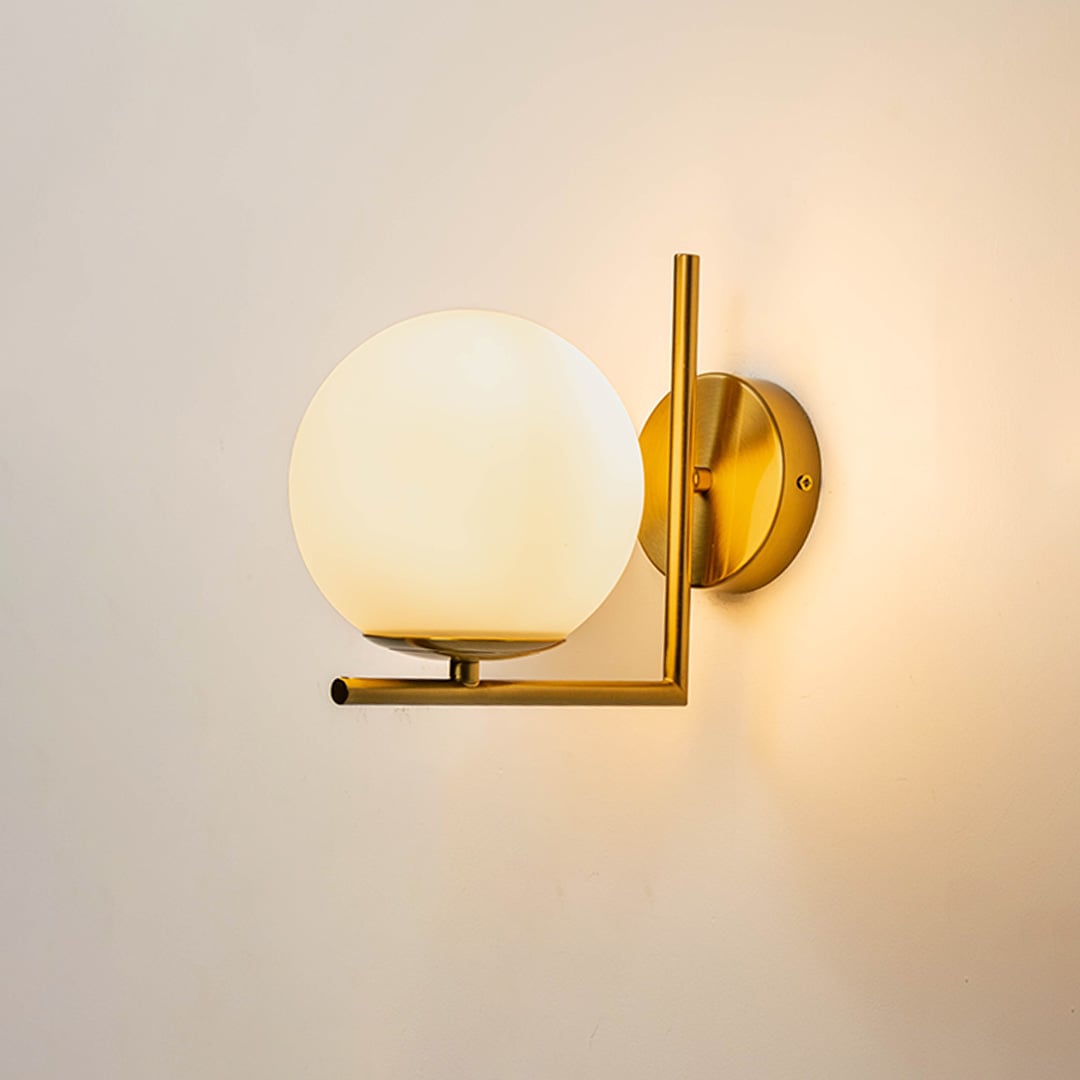 Wall lamp glowing with gold metal frame and frosted glass globe shade ideal for bedroom hallway and modern living spaces.