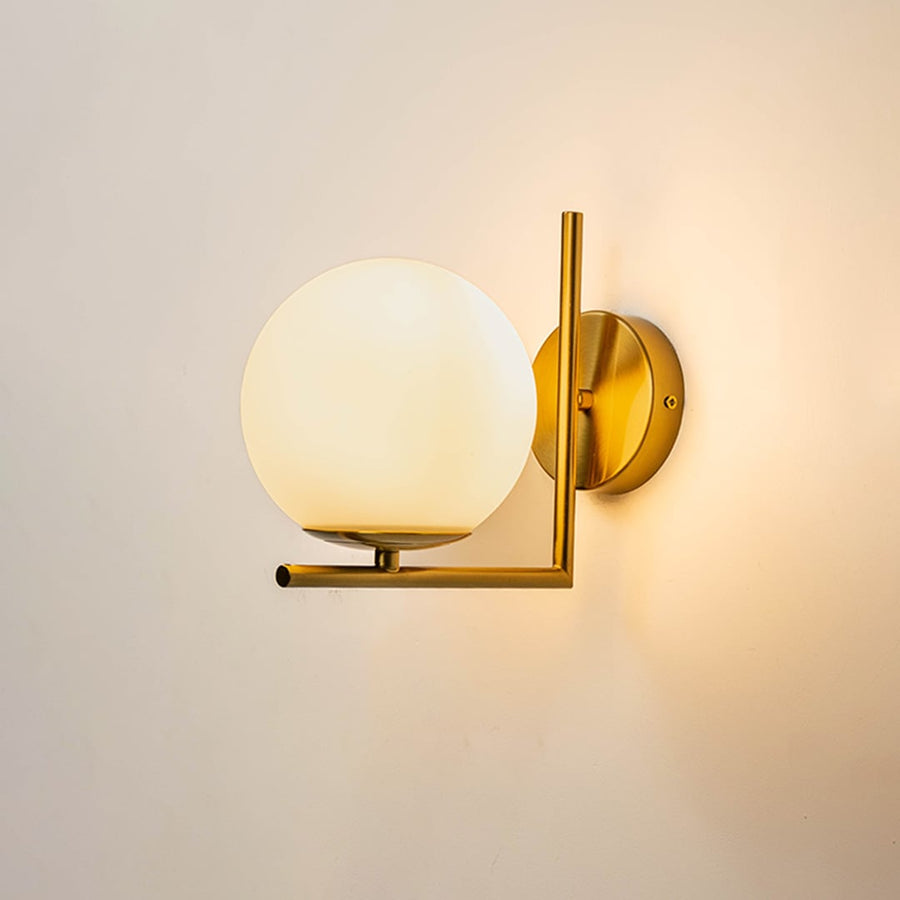 Wall lamp glowing with gold metal frame and frosted glass globe shade ideal for bedroom hallway and modern living spaces.