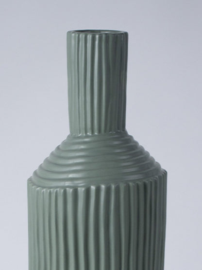 Closeup image of a matte sage green ceramic vase featuring combined vertical and horizontal ribbed patterns on an angled neck.