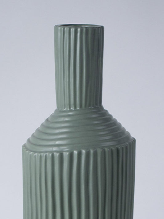 Closeup image of a matte sage green ceramic vase featuring combined vertical and horizontal ribbed patterns on an angled neck.