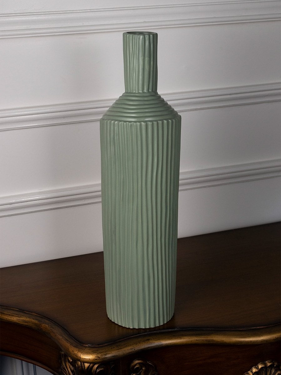Modern ribbed green ceramic vase standing on a white surface offering a fresh minimal decorative style.