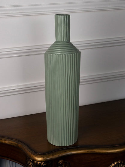 Modern ribbed green ceramic vase standing on a white surface offering a fresh minimal decorative style.