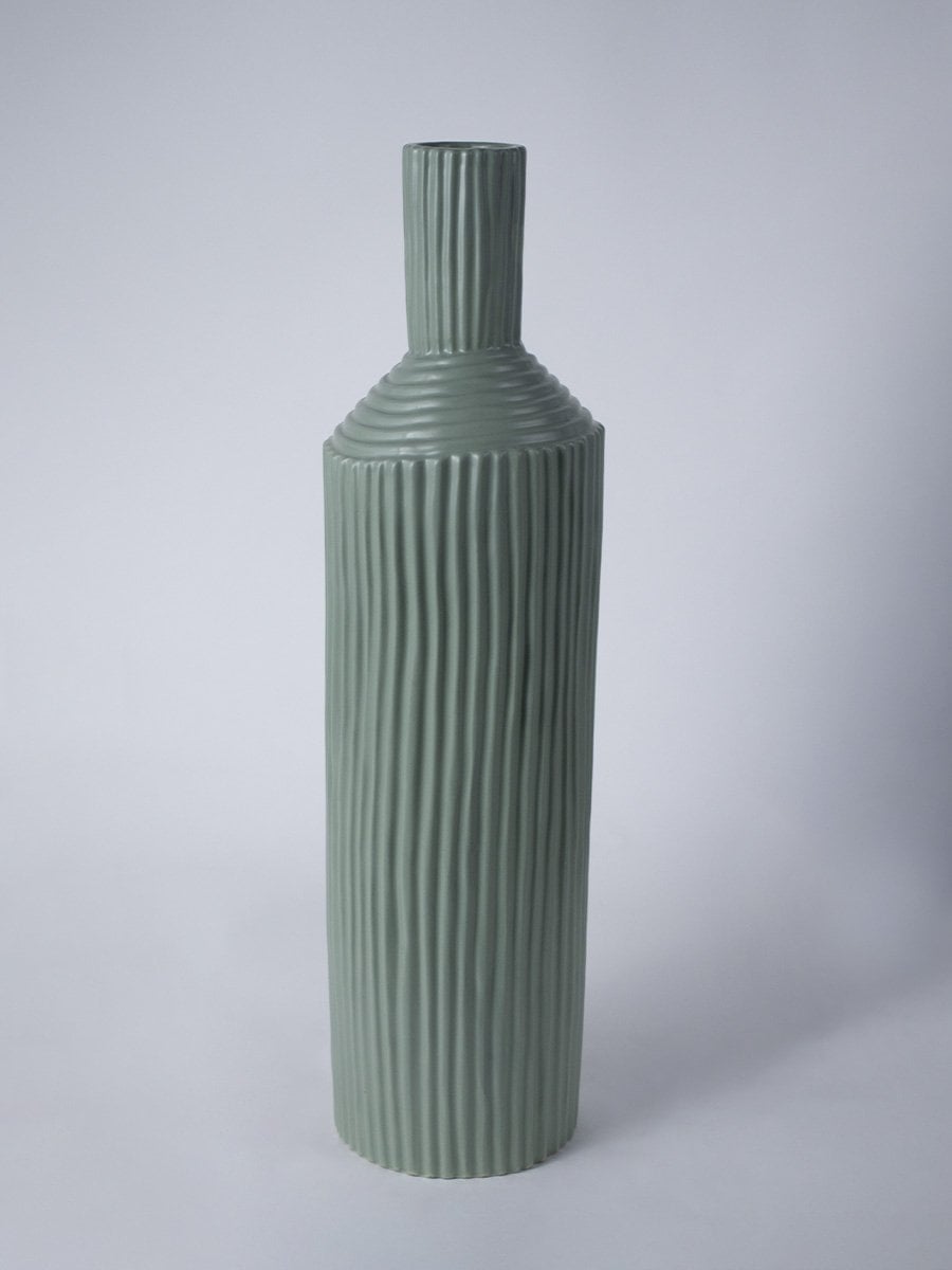 Tall ribbed green ceramic vase shown on a clean white background highlighting its modern sculpted design.