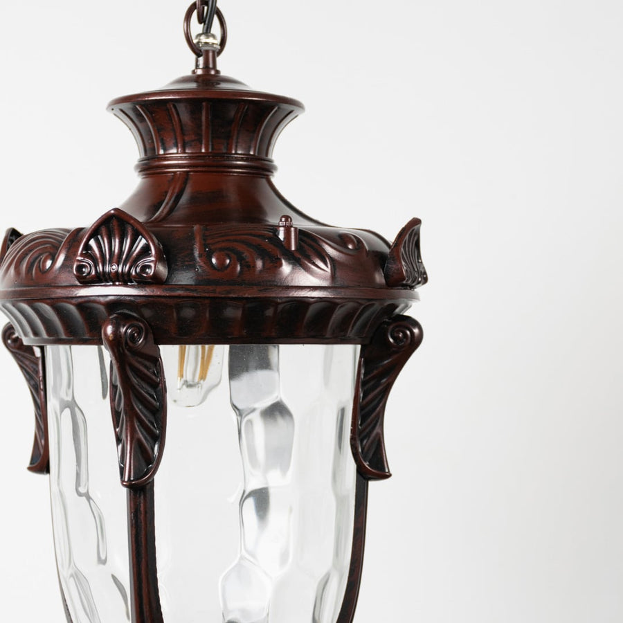 Antique copper metal lantern pendant light with detailed carved frame and clear glass for luxury outdoor spaces.