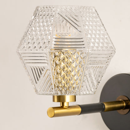 Closeup of gold metal wall light with geometric glass shade showcasing intricate pattern and premium finish for modern decor styling.