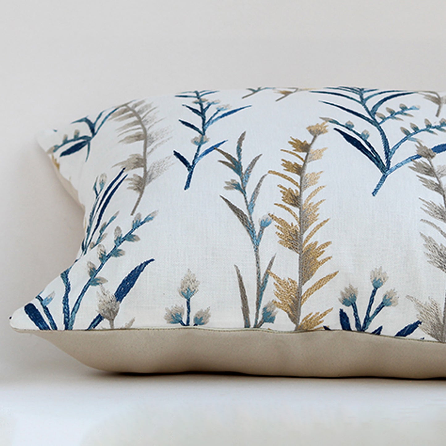 White cotton cushion cover with blue botanical leaf print for sofa bedroom seating and premium home decor styling.