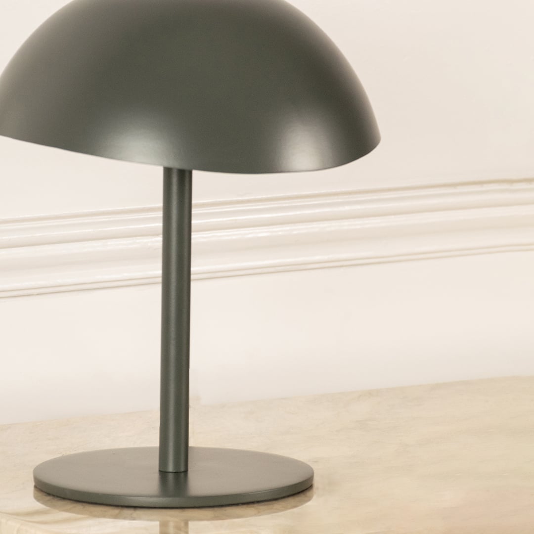 Green metal table lamp with dome shade and sleek stem base showcasing modern minimalist design and craftsmanship.