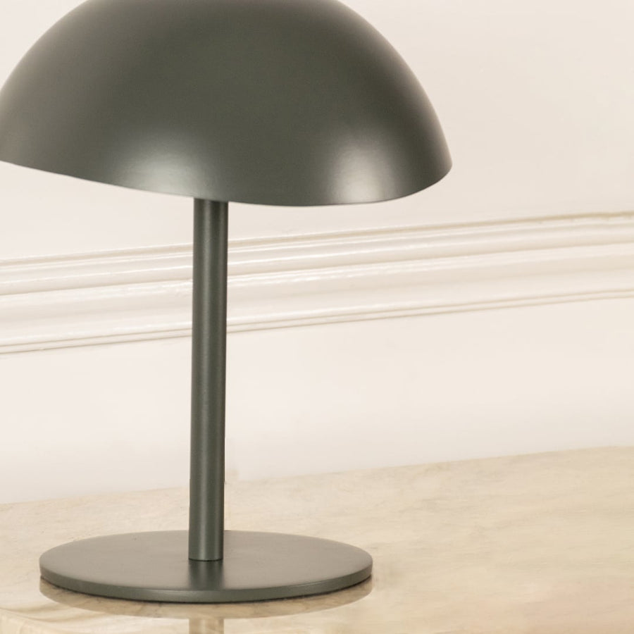 Green metal table lamp with dome shade and sleek stem base showcasing modern minimalist design and craftsmanship.