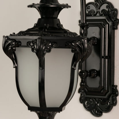 Close view of black metal lantern with detailed carving and frosted glass shade showing premium outdoor lighting design.