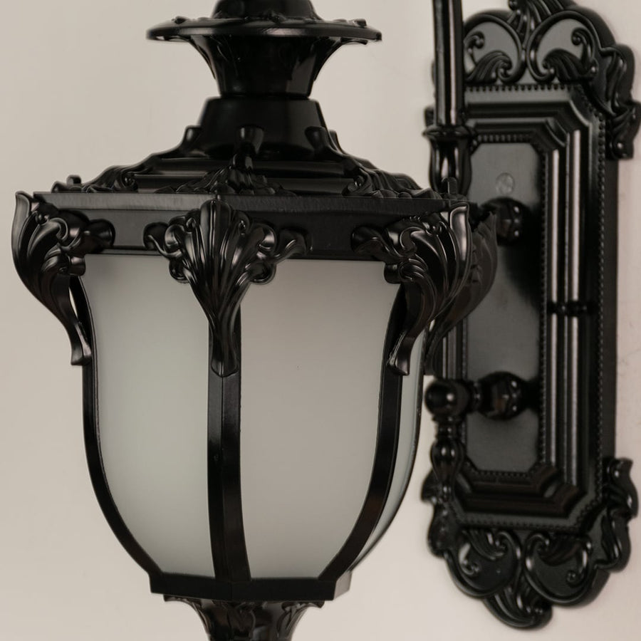 Close view of black metal lantern with detailed carving and frosted glass shade showing premium outdoor lighting design.