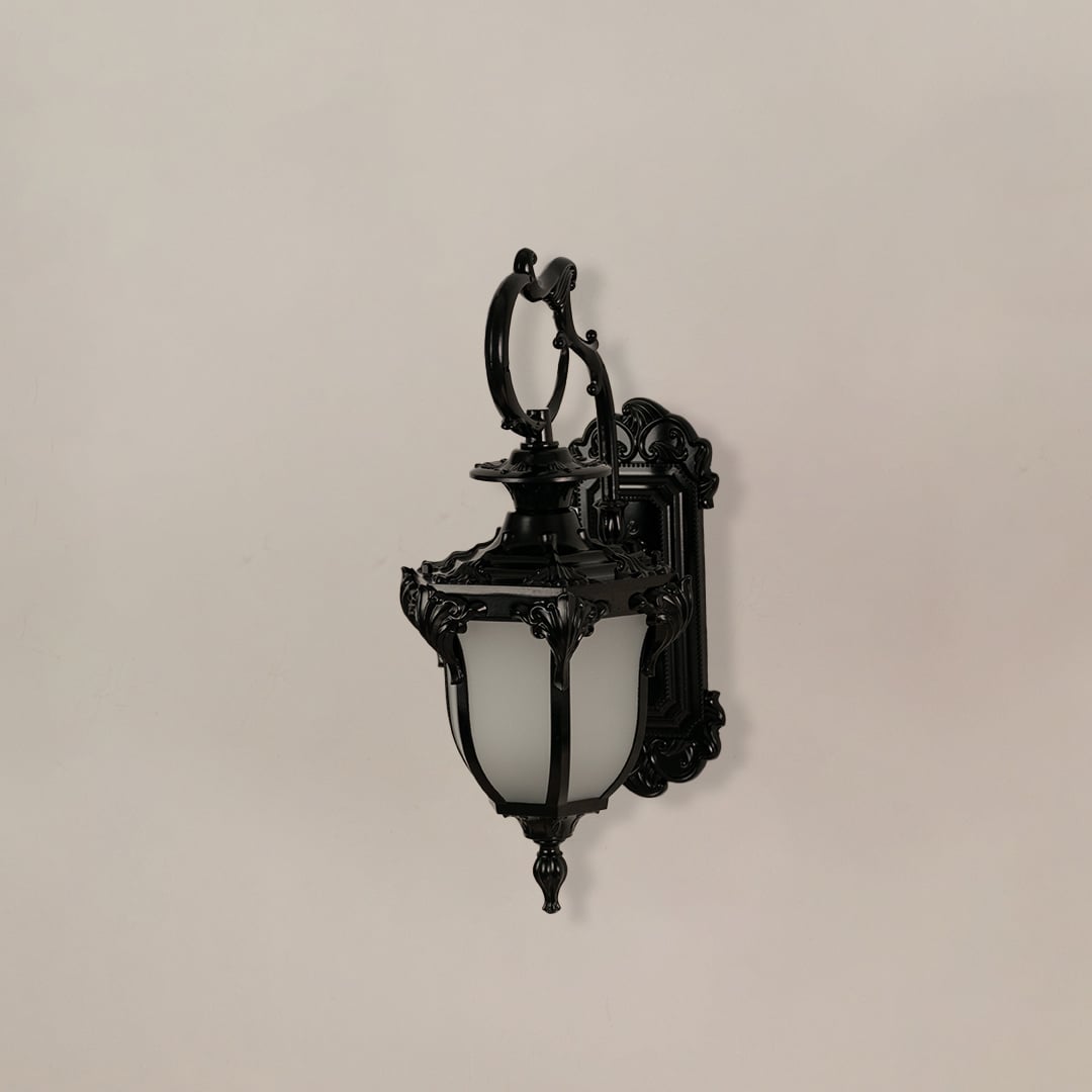 Black wall lantern with ornate metal frame and frosted glass shade ideal for outdoor pillars and entrance walls.