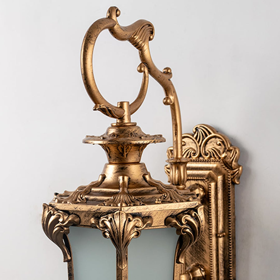 Closeup view of antique outdoor wall light with golden detailing and frosted glass for classic exterior lighting.