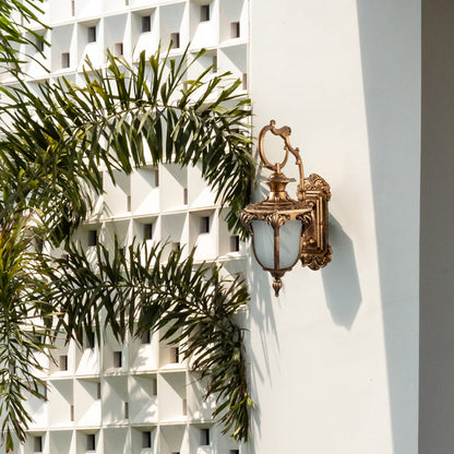 Antique outdoor wall light mounted beside an ornate entrance creates a warm and inviting outdoor ambiance.