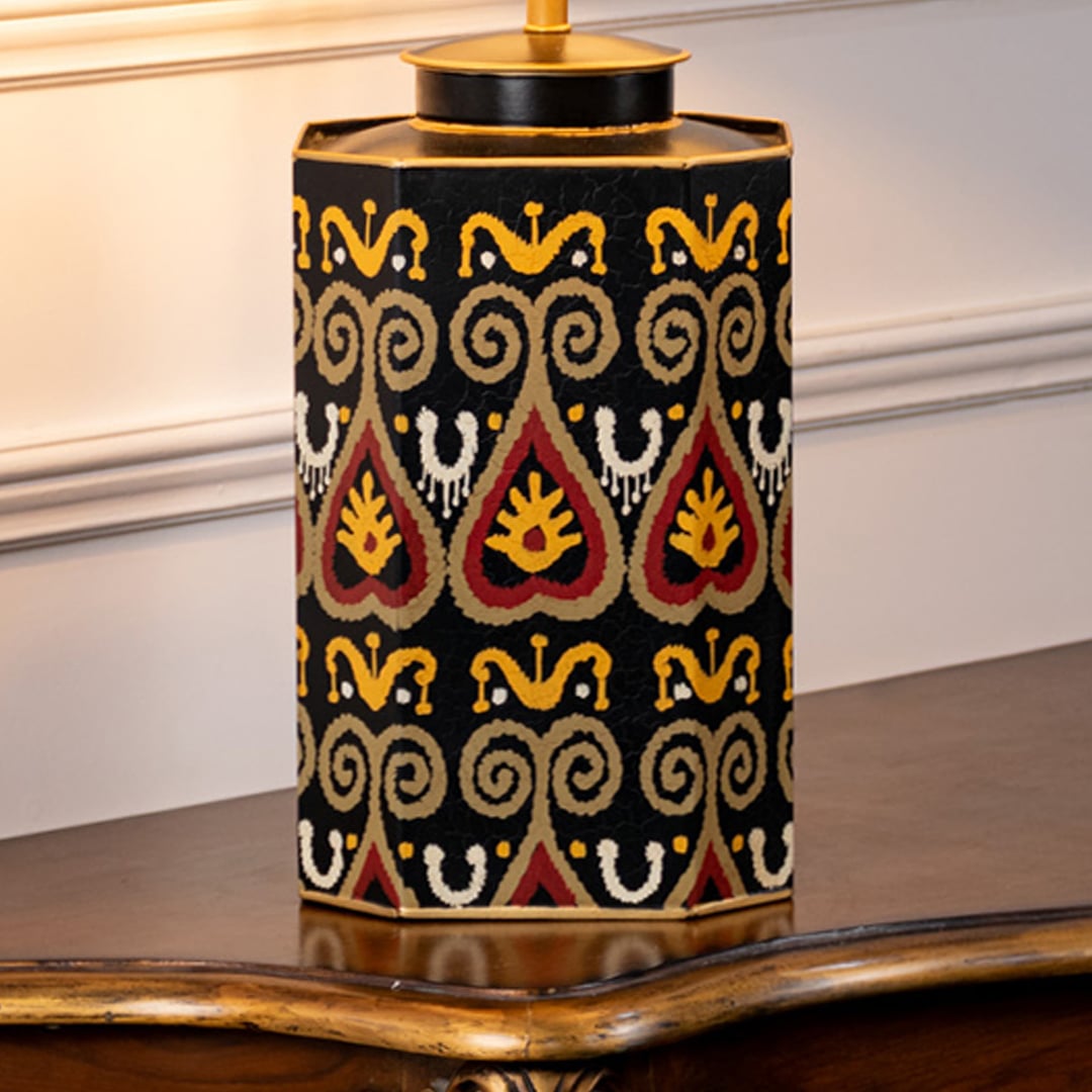 Table lamp closeup showing black ceramic base with colorful geometric pattern and gold detailing.
