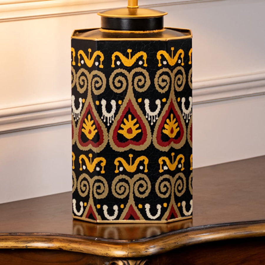 Table lamp closeup showing black ceramic base with colorful geometric pattern and gold detailing.
