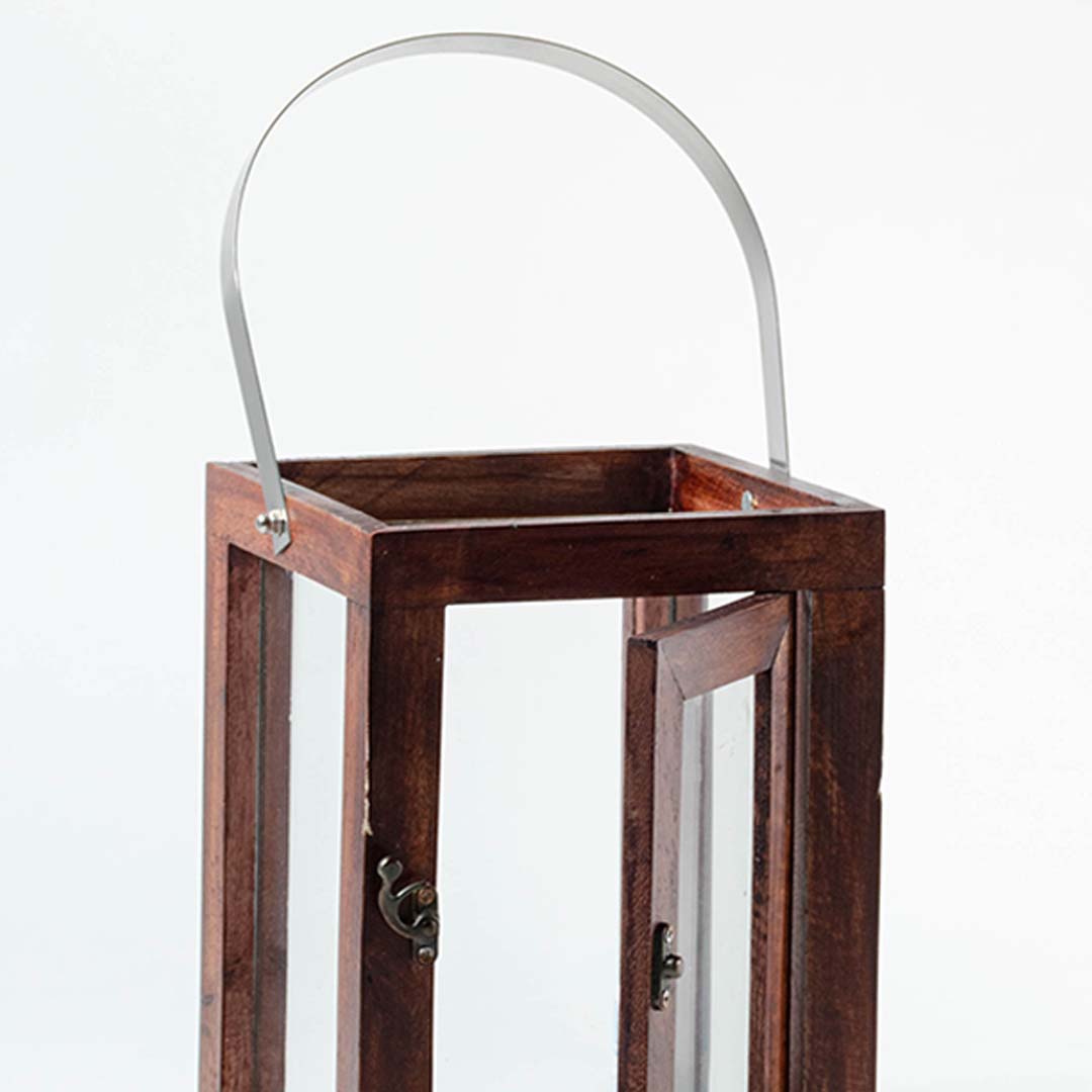 Closeup of wooden lantern with silver metal handle and clear glass panels for rustic decor styling.