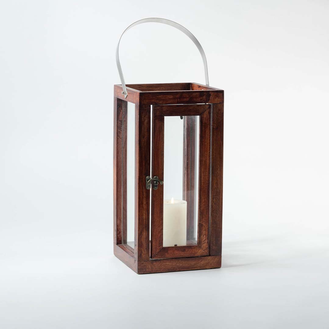 Elegant brown wooden lantern with glass panels and silver handle featuring glowing candle on white background decor.