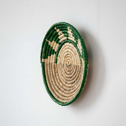 Side profile of handwoven bamboo wall plate in green beige tones showing detailed weave and natural texture.