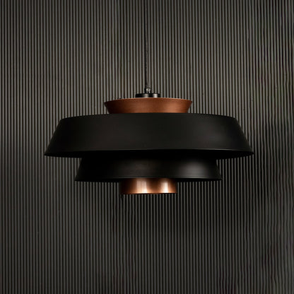 Modern black and copper pendant light displayed on dark background with lights off emphasizing its artistic layered finish.