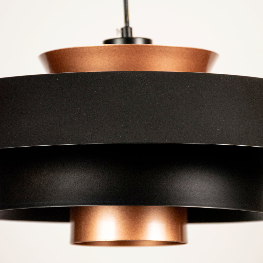 Black and copper metal pendant light closeup highlighting modern layered craftsmanship.